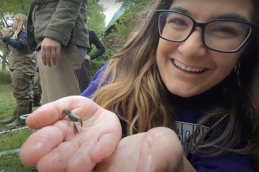 A student smiles at the camera with a water bug in her hands.