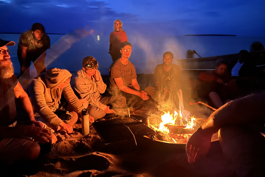People sit around a campfire.