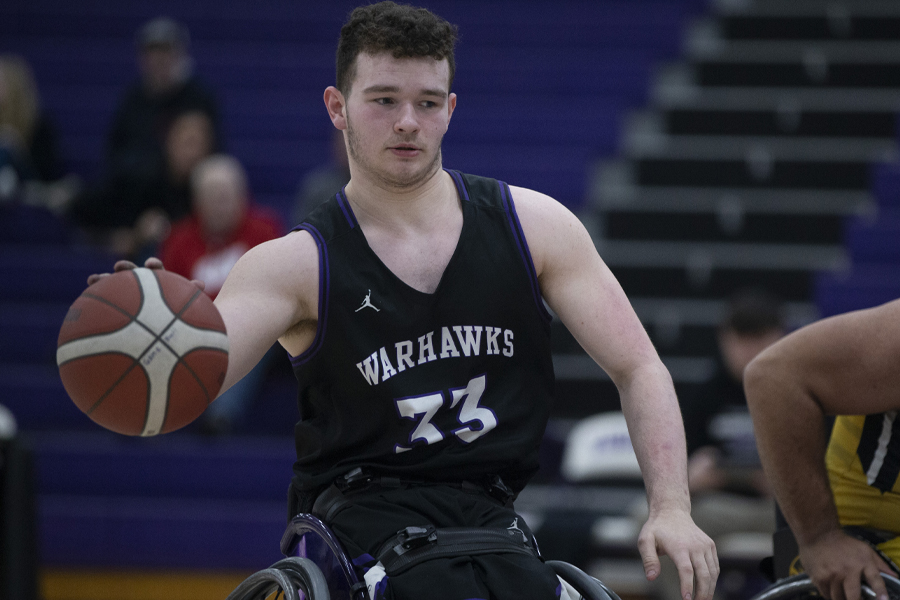A wheelchair basketball player dribbles the ball.