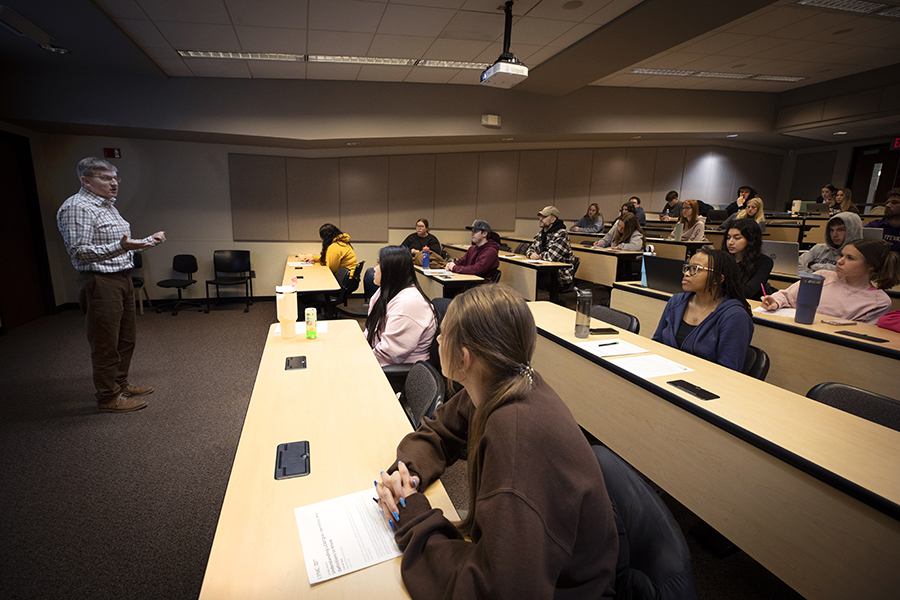 A faculty member speaks at the front of class.
