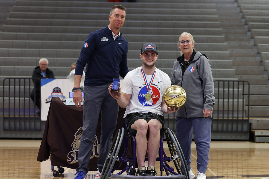 Thomas Oberst poses on the court and holds a golden basketball.
