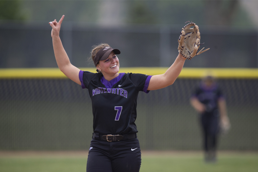A Warhawk softball player smiles with her hands in the air.