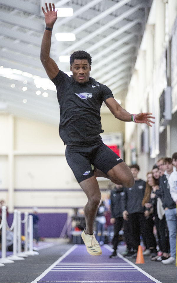 Shelvin Garrett jumps with his arms in the air as he competes in a long jump.