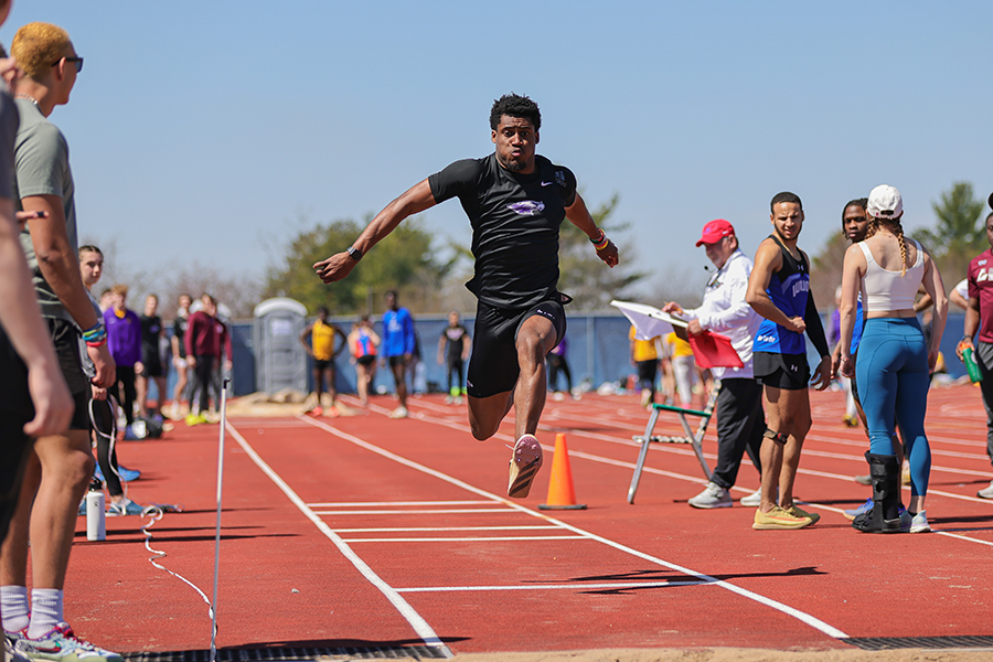 Shelvin Garrett is mid-air in an outdoor triple jump competition.