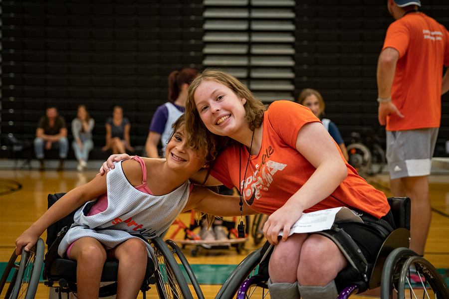 Hannah Smith wraps her arm around another person as they pose for a photo on a basketball court.