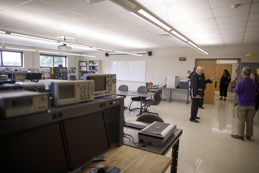 People gather in the electrical engineering room that has tables and other electrical equipment.