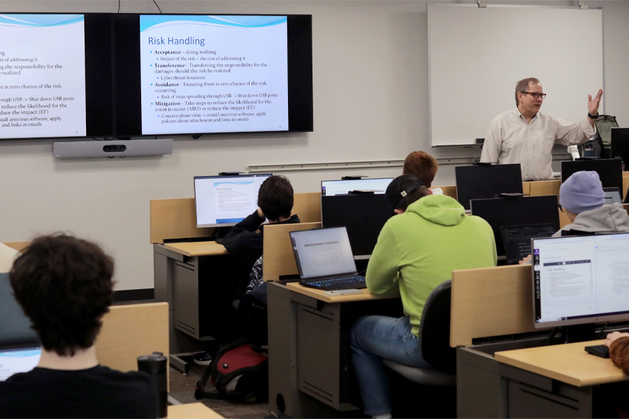 A faculty member speaks at the front of a class. 