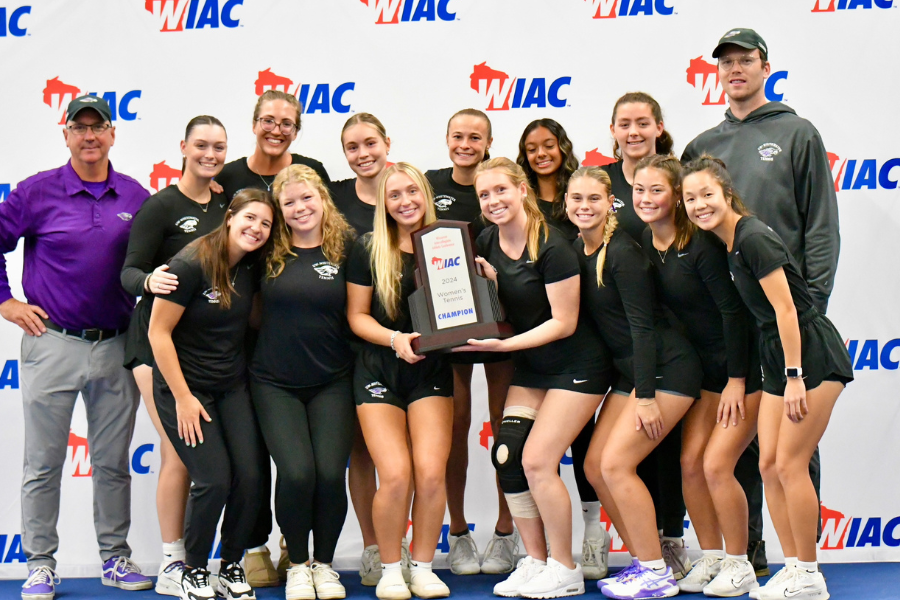 student athletes and coaches standing and holding a plaque