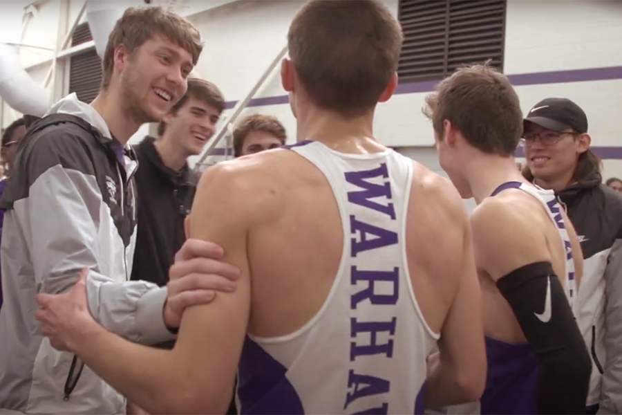 A cross country runner wearing a Warhawks jersey is greeted by people in the crowd.