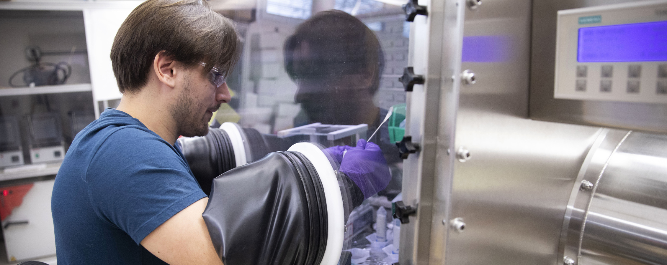 A student works in a glove box in the chemistry lab.