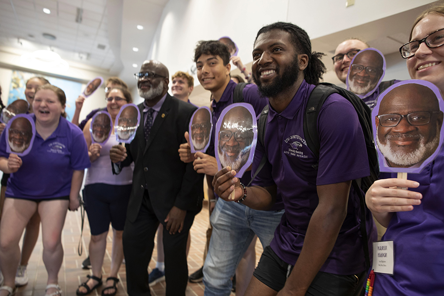 Chancellor King stands with a large group of students who are holding a paper cut out of his head.