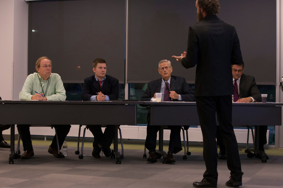 Group of peoaple together sitting at table and doing elevator pitch.
