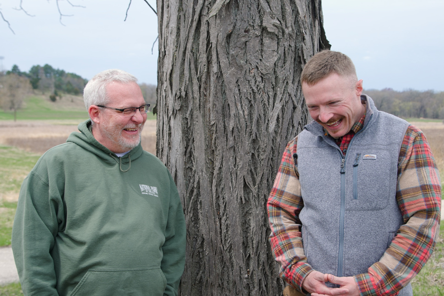Two people against tree smiling