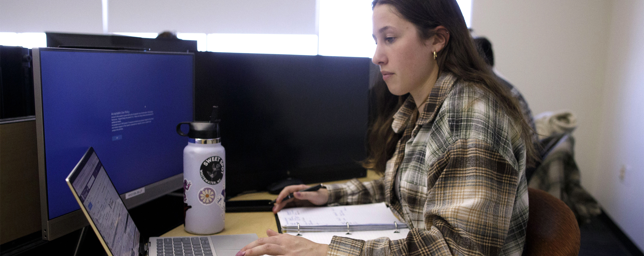 A person sitting at a table works on a laptop.