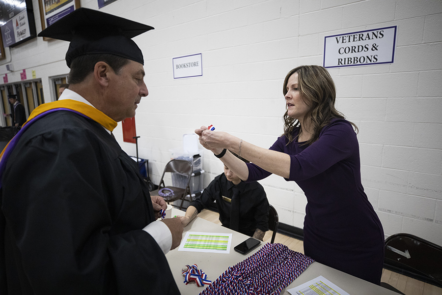 Amy Moore hands a pin to a graduate wearing academic regalia.