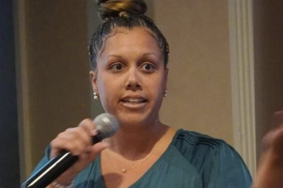 A person in a green shirt speaks into a microphone.