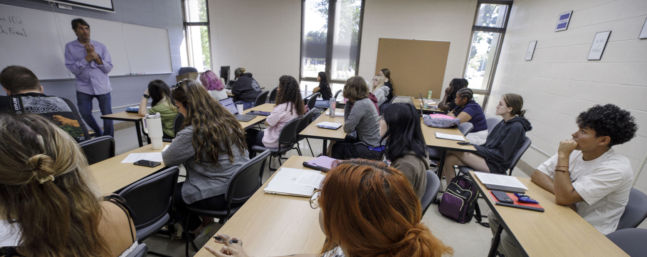 A faculty member teaches at the front of a small class.