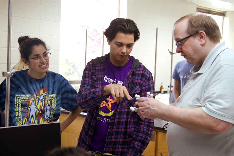 Two students and a faculty member look at a module of molecules.