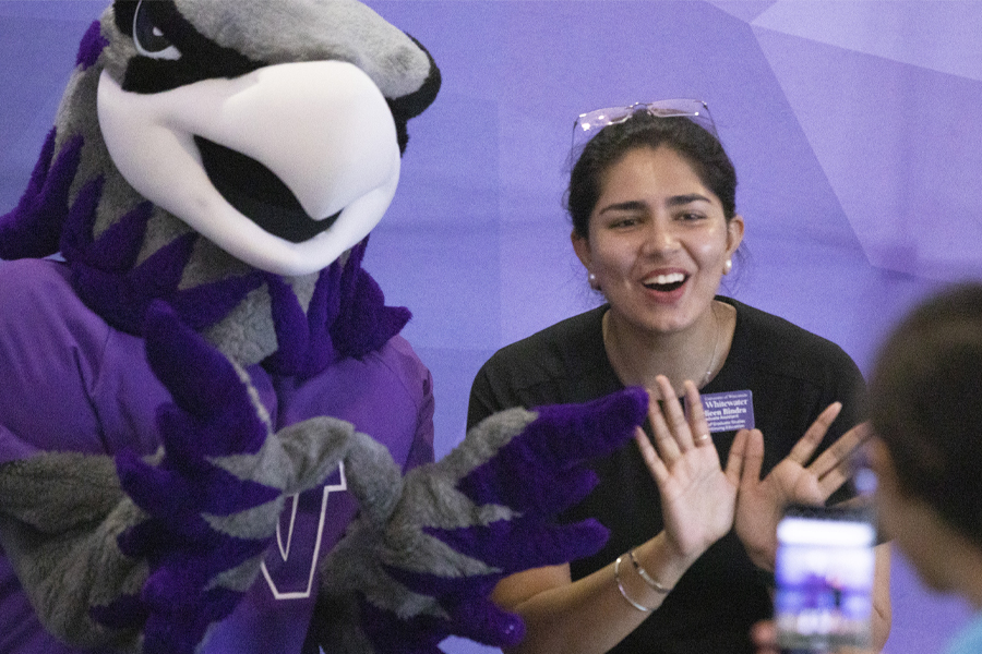 Willie Warhawk poses with another person in front of a purple backdrop.